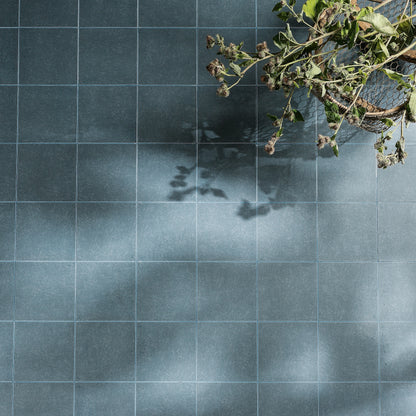 Dark blue matte-finish ceramic floor tiles with subtle texture and light gray grout from adventuras navy field porcelain series