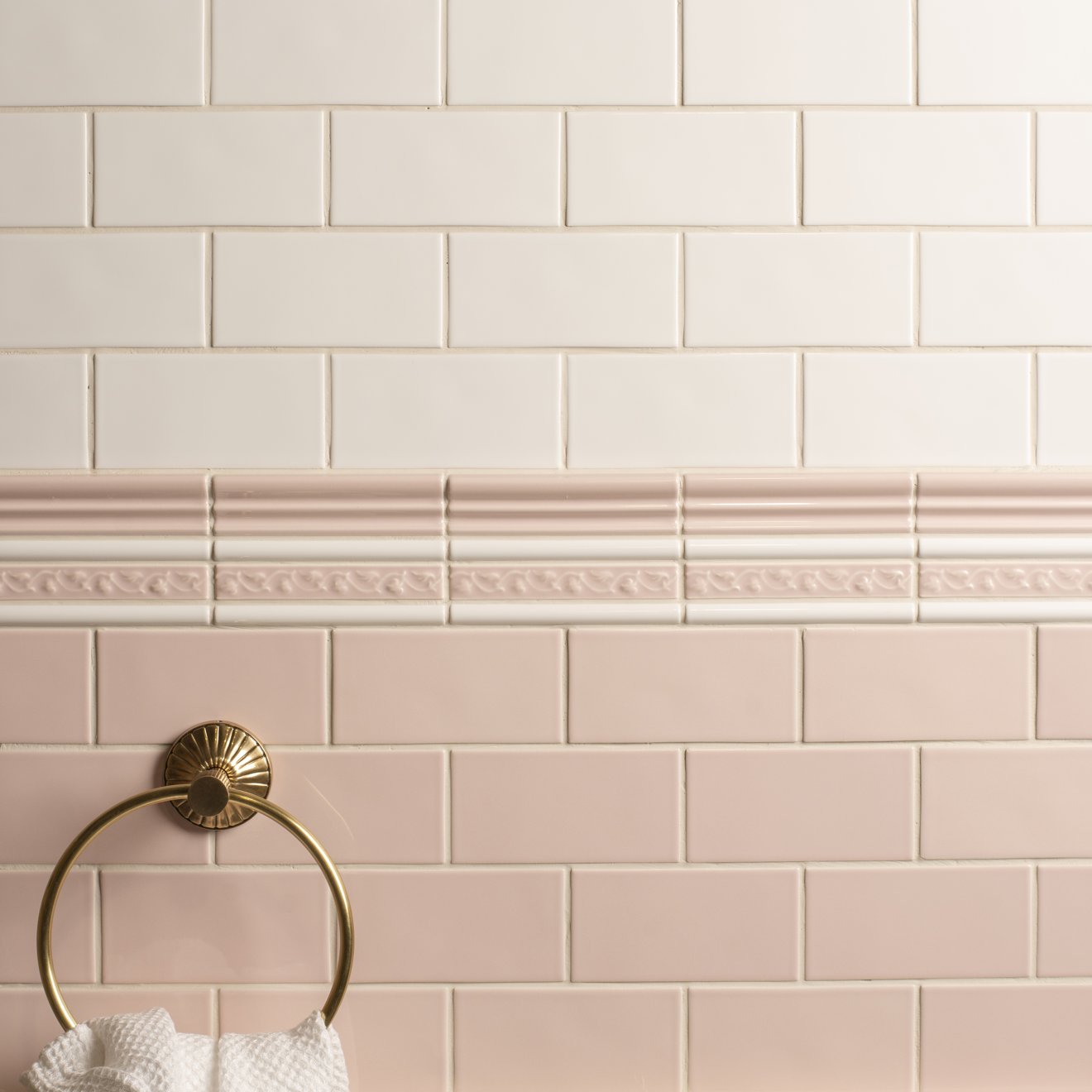 Beaulieu moulding clare gold-toned towel ring with sunburst design mounted on soft pink and cream subway tile wall