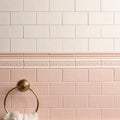 Beaulieu moulding clare gold-toned towel ring with sunburst design mounted on soft pink and cream subway tile wall