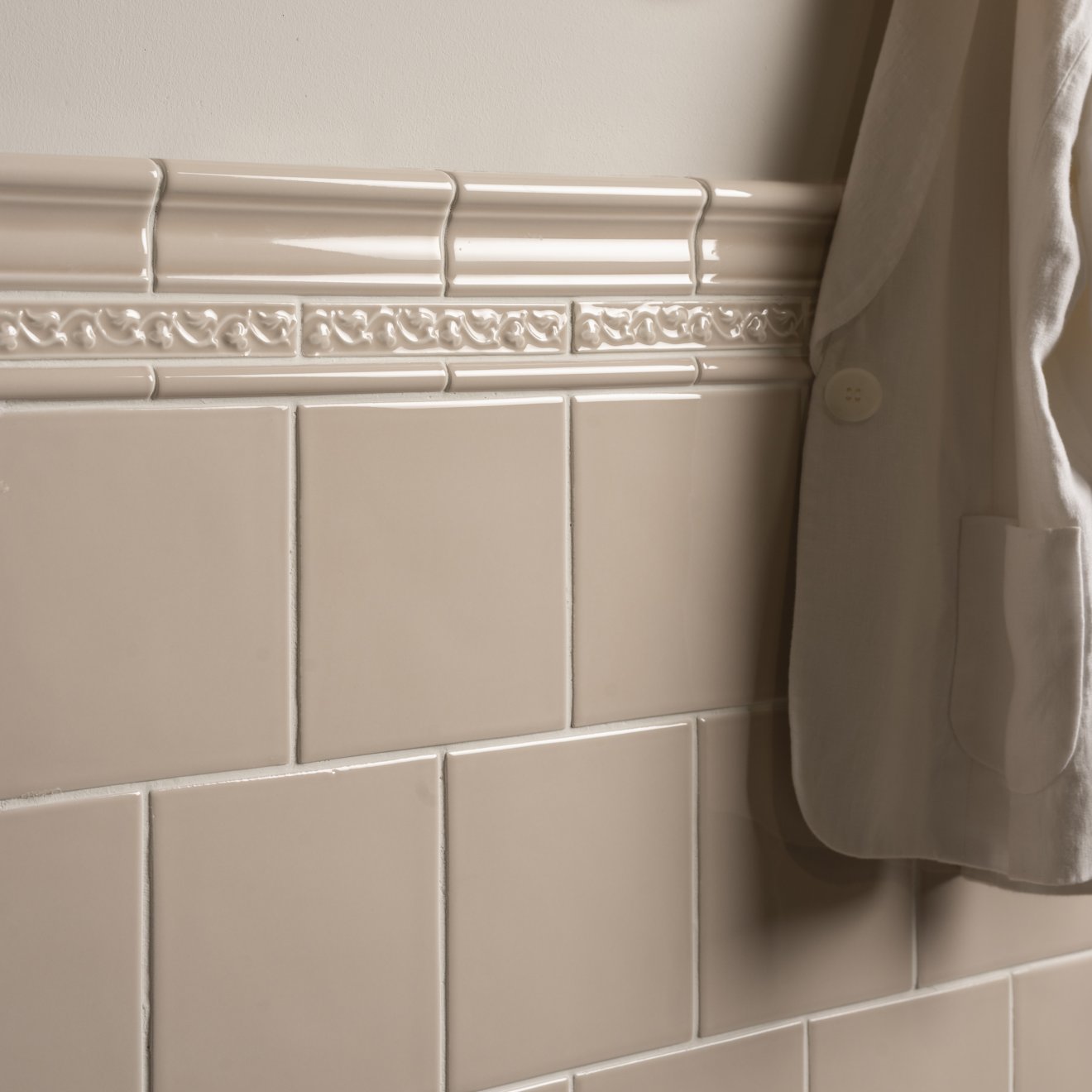 Cream-colored ceramic tile border with ornate raised scrollwork design from beaulieu moulding hadleigh