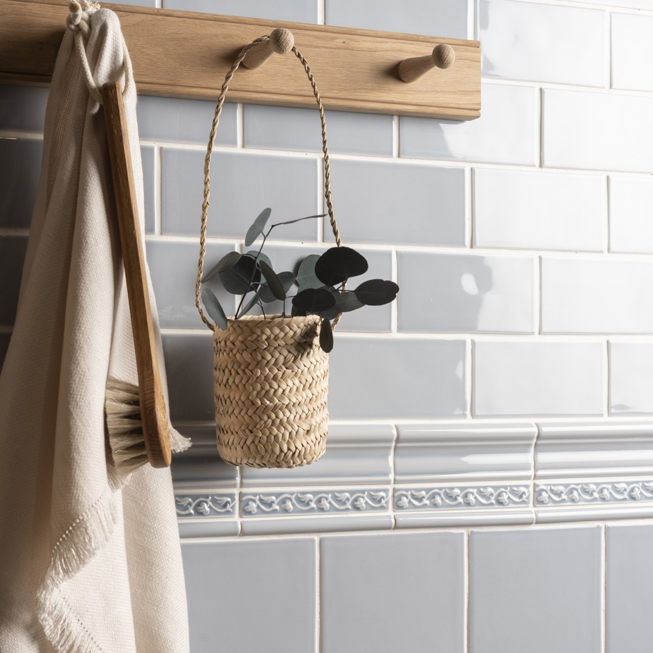 Beaulieu moulding snape woven natural fiber hanging planter with braided rope handle holding dark green eucalyptus leaves