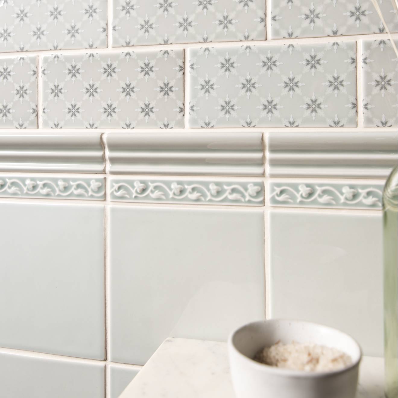 Beaulieu moulding Sudbury featuring gray subway tiles with subtle snowflake pattern and ornate white decorative border
