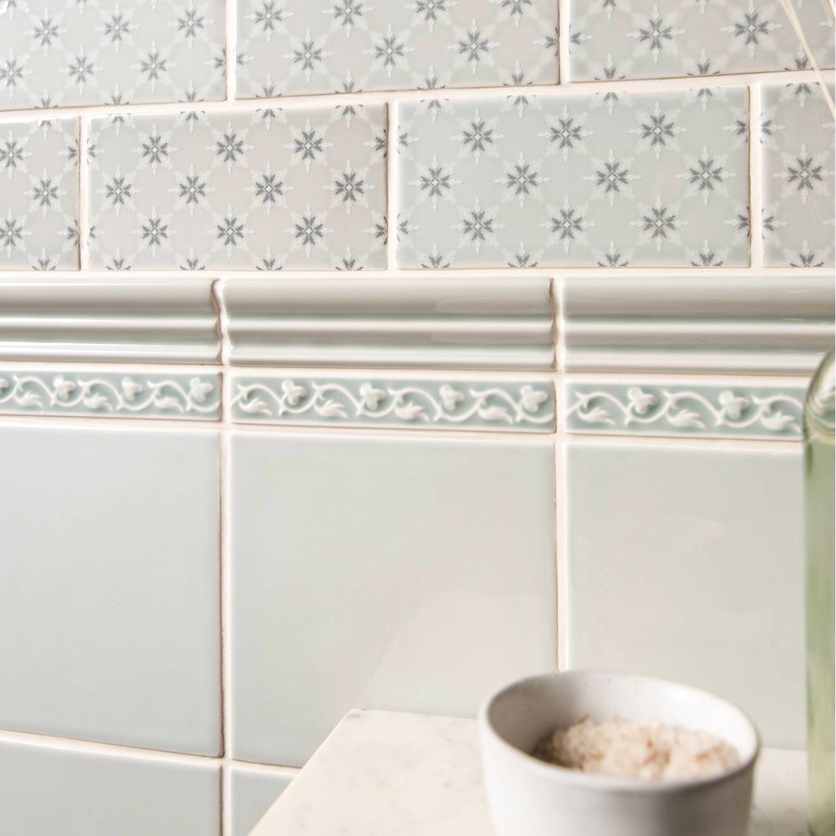 Beaulieu moulding Sudbury featuring gray subway tiles with subtle snowflake pattern and ornate white decorative border