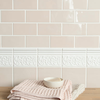 Beige tiles with decorative border and folded towel on wooden surface