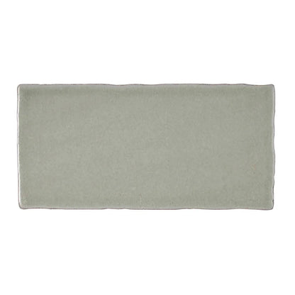 A rectangular matte finished ceramic tile in soft sage green with slightly irregular edges from Carnival Sella Grey Glazed Tile