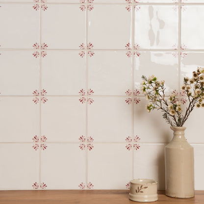 Decorative wall tiles with floral patterns and a vase with flowers on a wooden surface.