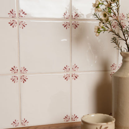 Decorative tiles with floral patterns on a wall next to a vase and small bowl.