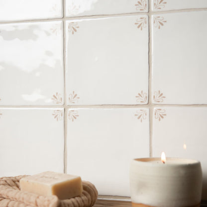Candle and soap on a woven mat with a tiled wall background