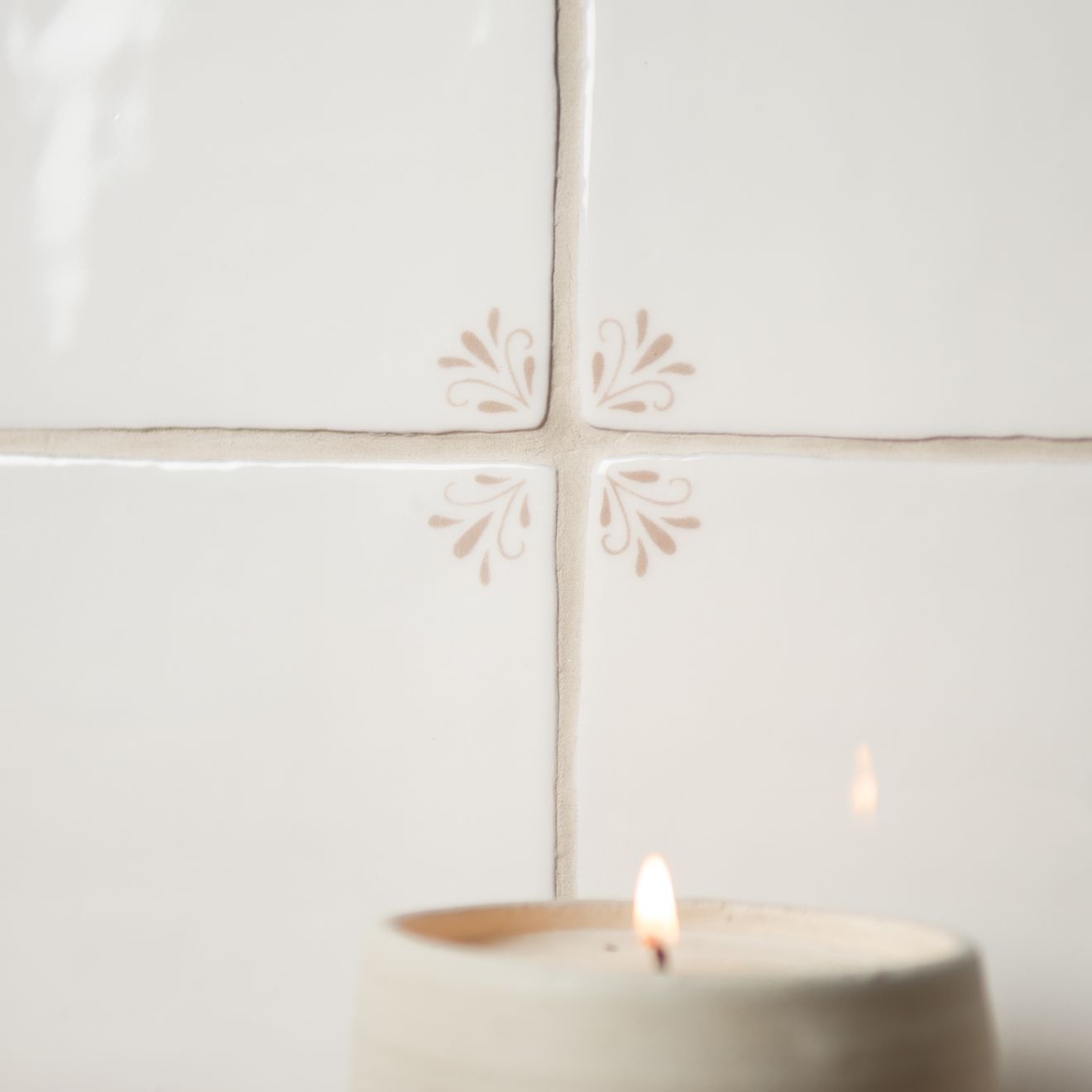 Candle on a white tile wall with decorative cutouts