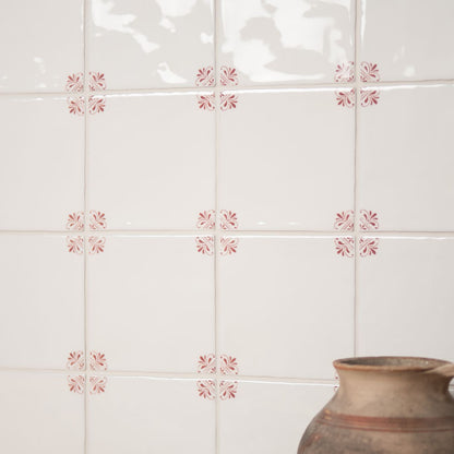 Decorative tiles with pink floral patterns on a white wall with a ceramic pot.