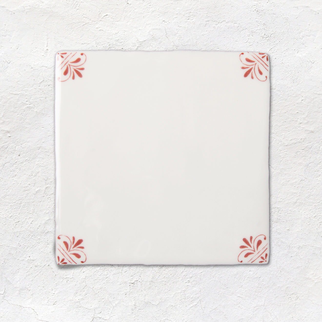 White ceramic tile with red floral patterns on a textured white background