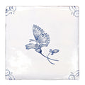 White ceramic coaster featuring a delicate blue hand-painted butterfly on a flower with ornate corner motifs english delft