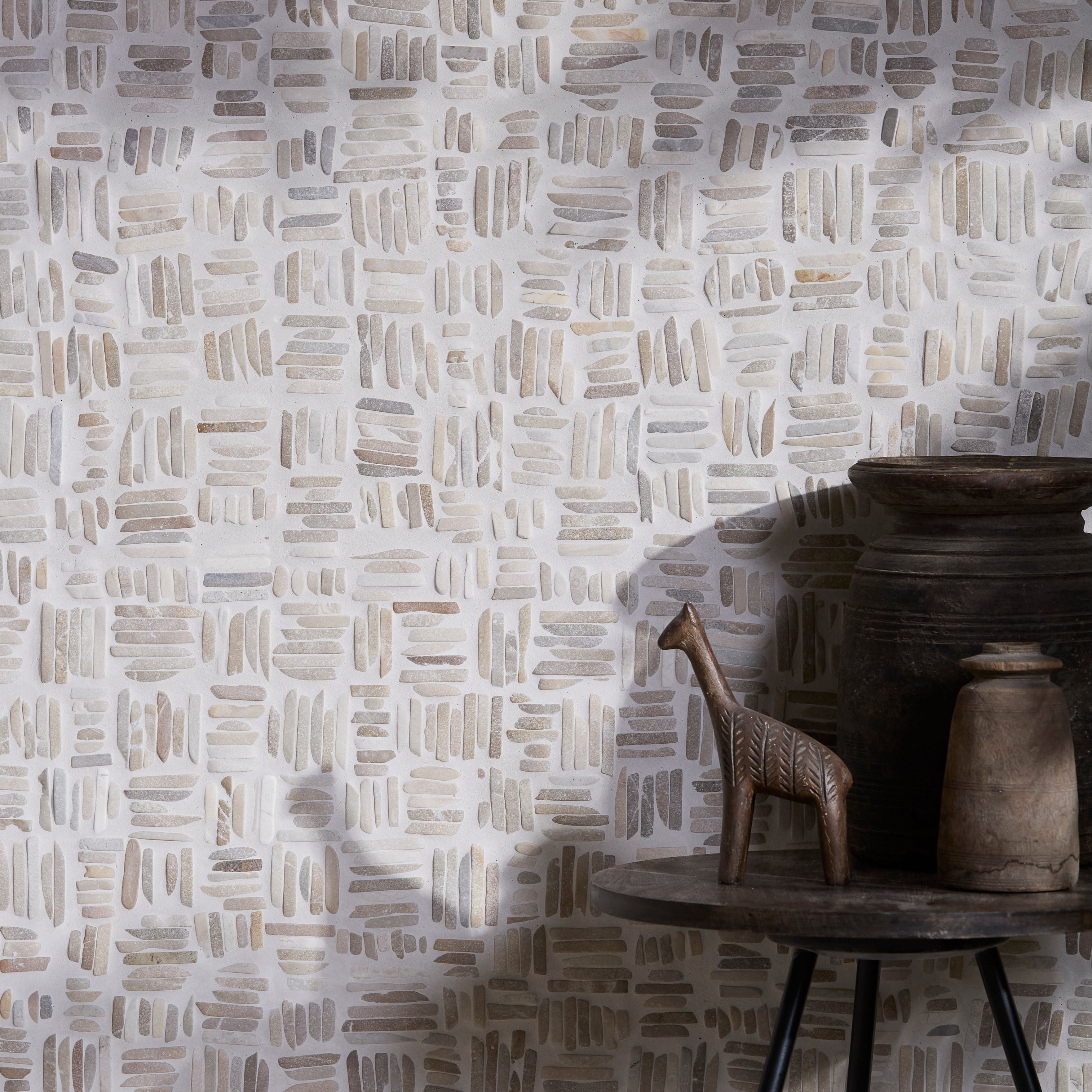 Patterned wall in Enso Organic Basketweave Limestone Mosaic Tiles with a wooden table and decorative items