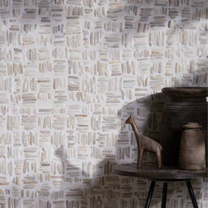 Patterned wall in Enso Organic Basketweave Limestone Mosaic Tiles with a wooden table and decorative items