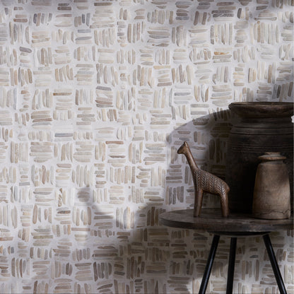Textured wall in Enso Organic Basketweave Limestone Mosaic Tiles with a small wooden giraffe figure and pot on a table.