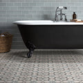 Bathroom with a black freestanding bathtub against a gray tiled wall.