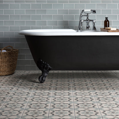 Bathroom with a black freestanding bathtub against a gray tiled wall.