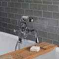 Chrome bathtub faucet with handheld shower head against a gray tiled wall.