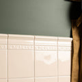 Close-up of a tiled wall with decorative border against a gray wall.
