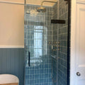 Brass showerhead with rounded polished finish and integrated handle shown with jaipur storm rectangle glazed tile background