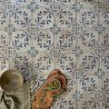 A rustic olive wood cutting board with textured surface and visible grain featured with paris isabelle patterned terracotta tile