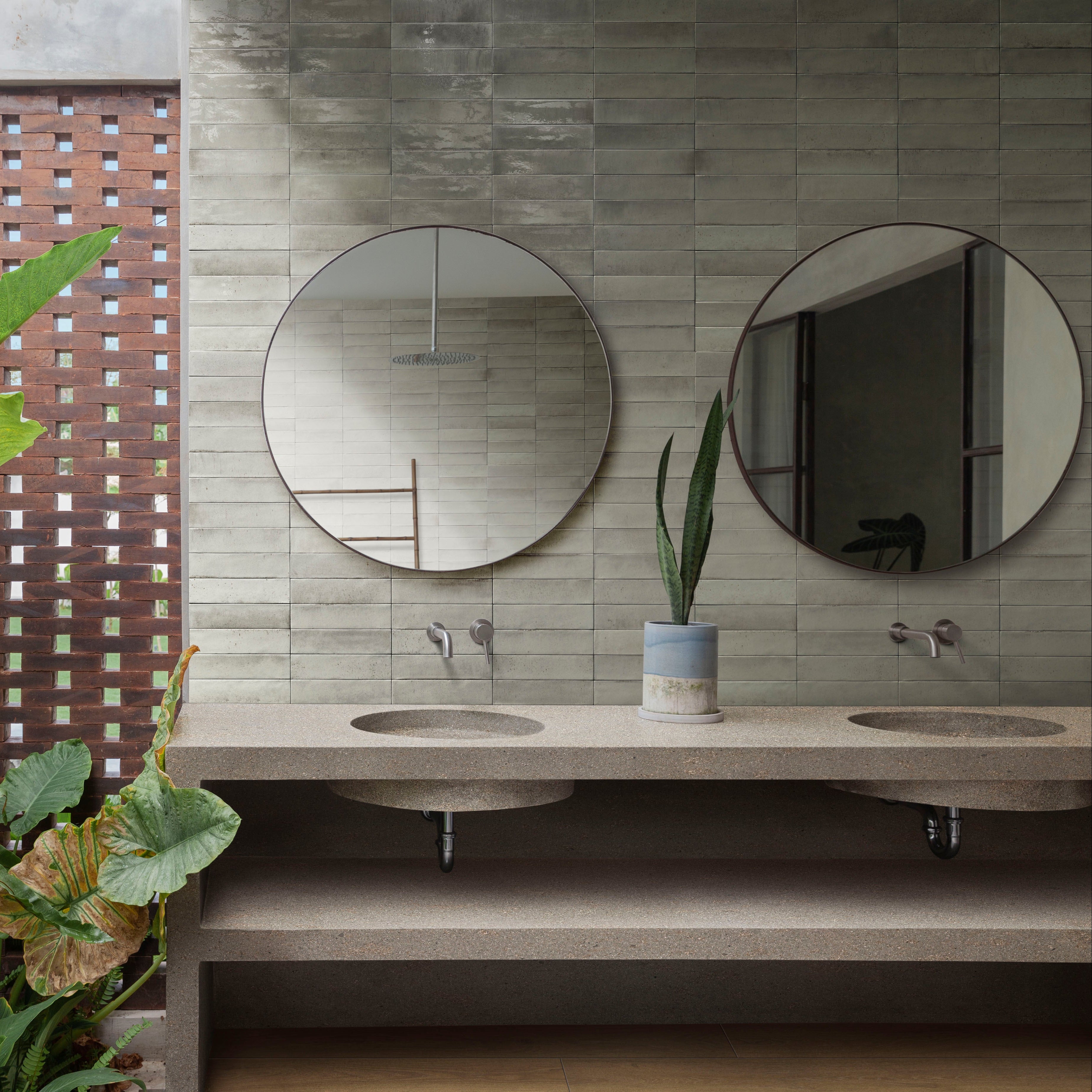 Modern bathroom with concrete sink, round mirrors, and plants