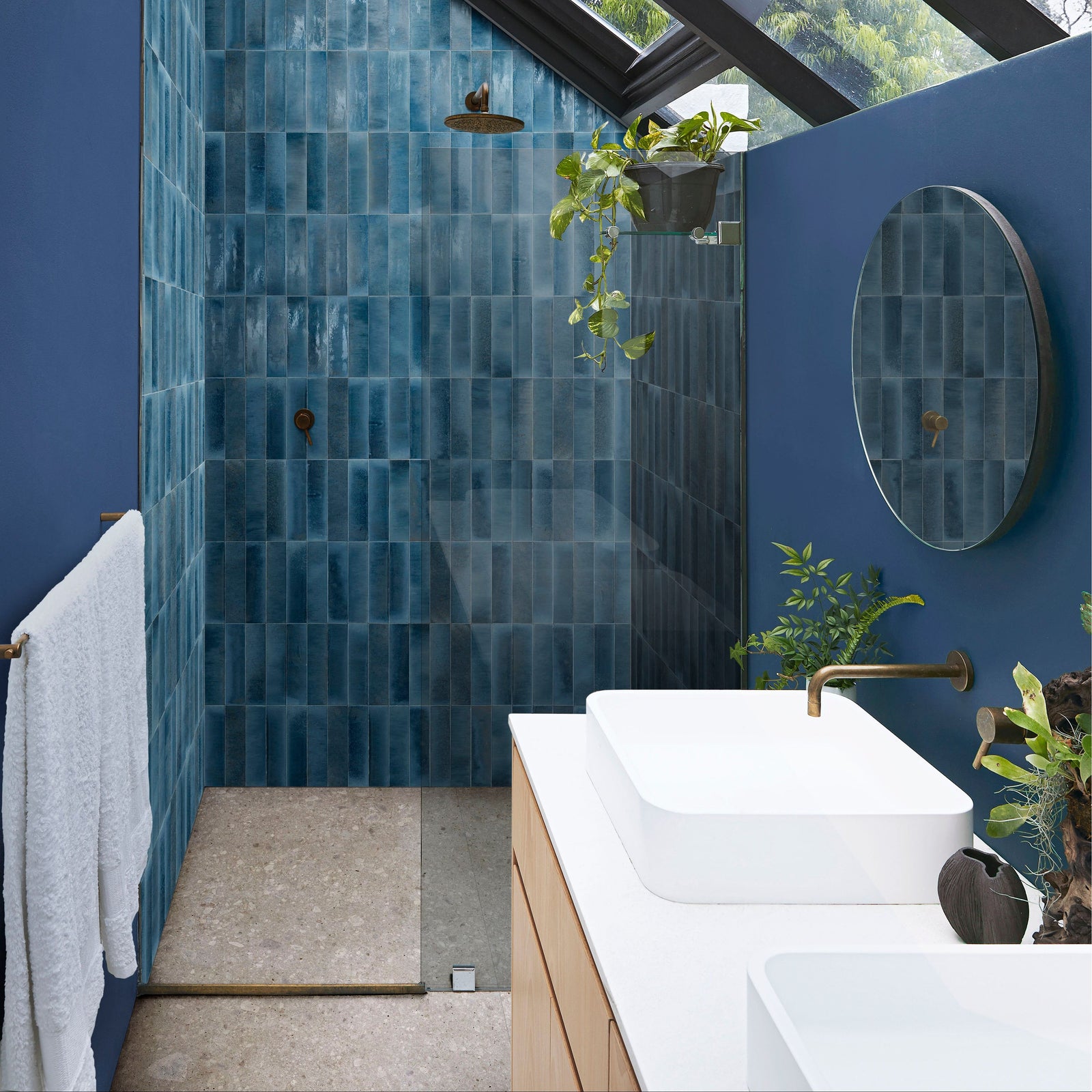 The bathroom features luminous lume blu china blue tiled shower wall with glossy glazed vertical rectangular tiles