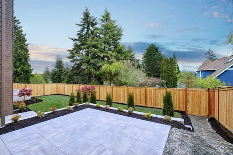 Beige stone outdoor flooring tiles with embedded recessed lights and bordering greenery on a stone pathway.