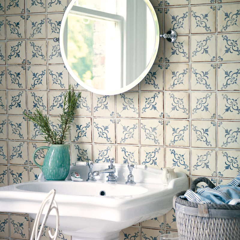 A round chrome finished wall mounted mirror with a sleek minimalist design displayed with paris isabelle patterned terracotta tile