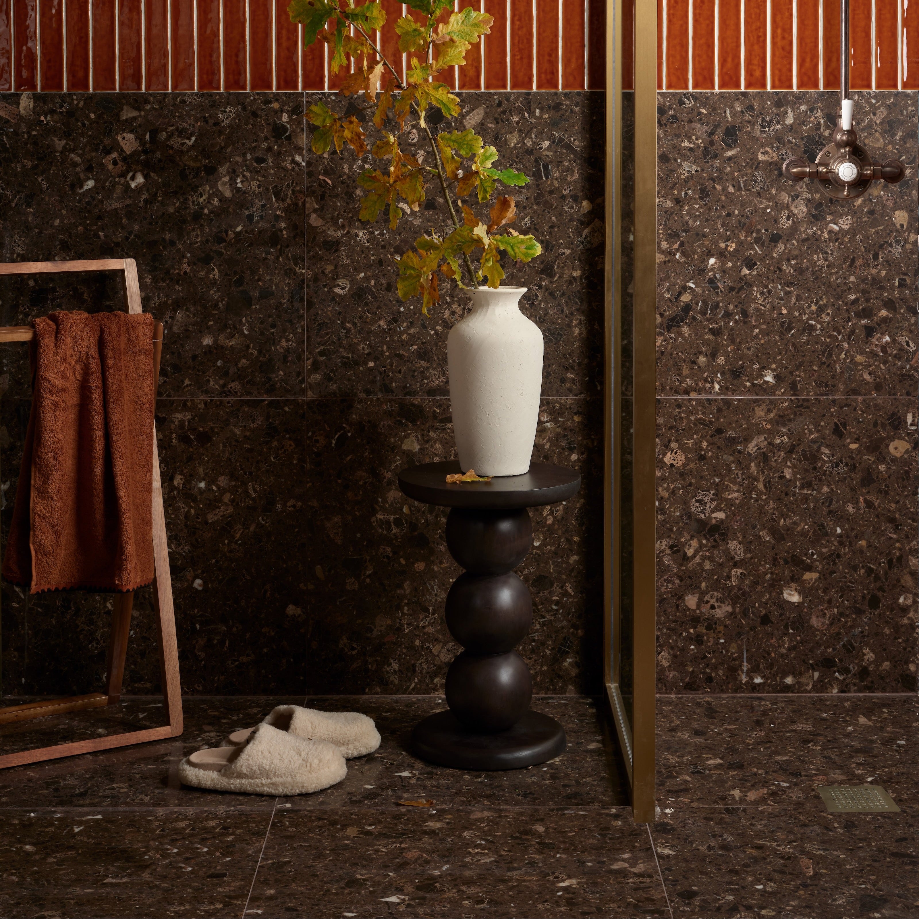 Rialto Terrazzo Ca'Doro Honed dark brown terrazzo tiles with a white ceramic vase