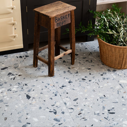 Rialto Terrazzo Castello Honed grey terrazzo tiles with a rustic wooden stool