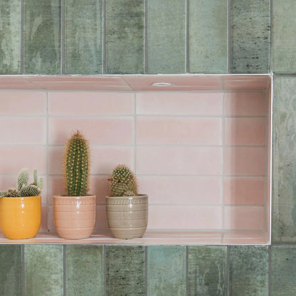 Three cacti in pastel ceramic pots yellow peach and beige on a pink tiled shelf featuring south cliff rose brick tile