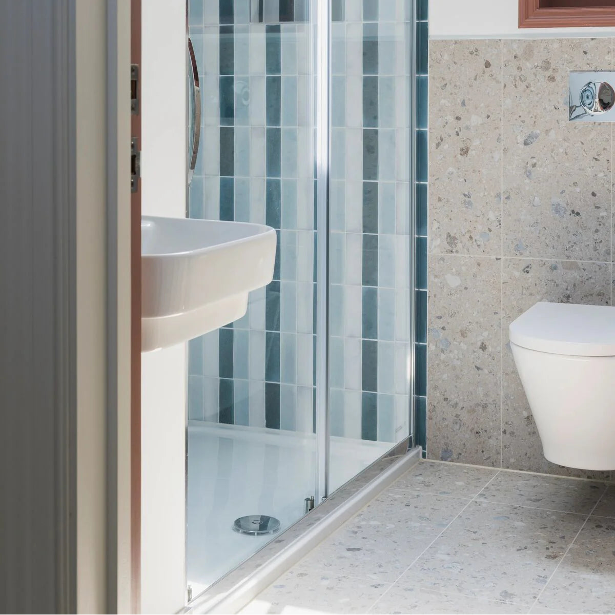 White ceramic wall-mounted sink with sleek modern design paired with teal brick tile background