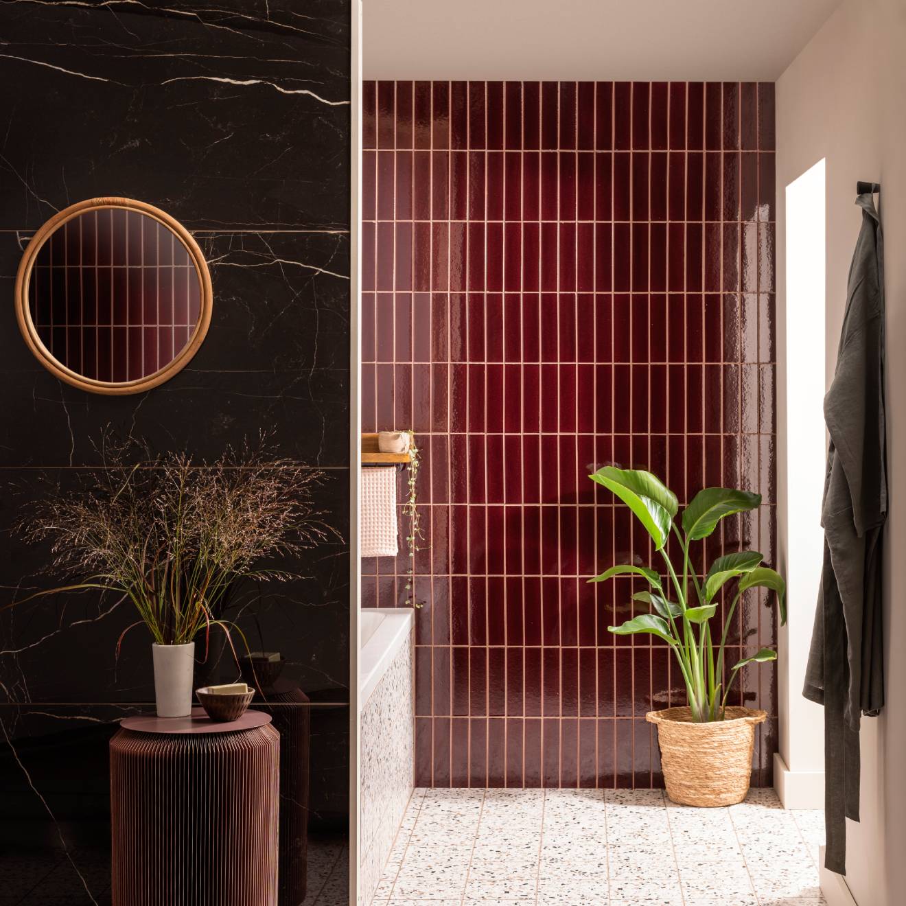 Bathroom featuring glossy black marble walls with a rattan mirror and burgundy vertical tor brick tile with a potted plant
