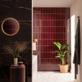 Bathroom featuring glossy black marble walls with a rattan mirror and burgundy vertical tor brick tile with a potted plant