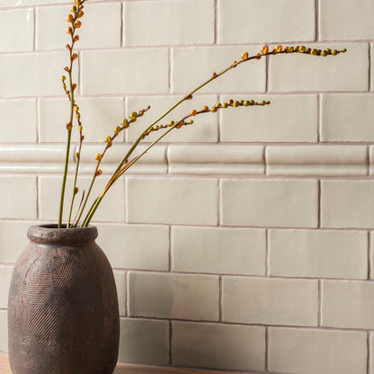 Dark gray textured ceramic vase torus moulding tern holding slender green stems with budding yellow flowers