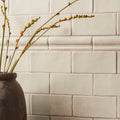 Dark textured ceramic vase torus moulding tern holding slender green stems with budding yellow flowers