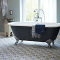 Black clawfoot bathtub with white interior and chrome fixtures showcased on abbey fountains patterned tile floor