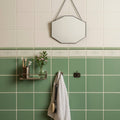 Hexagonal mirror with thin black frame hanging from chain in acanthus jade breeze on brilliant white setting