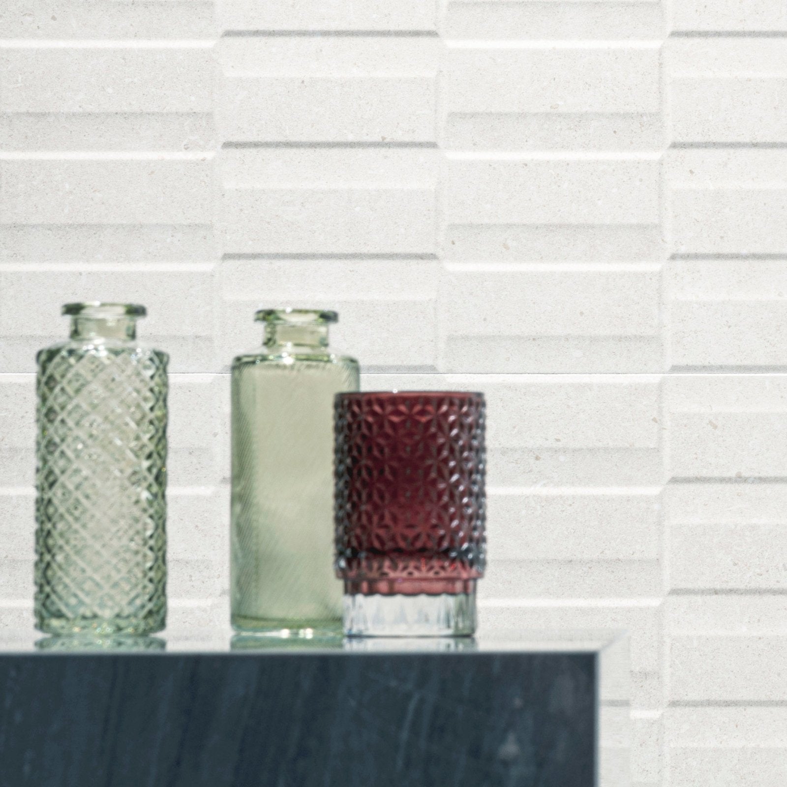 Three glass vases in clear green, pale green, and deep burgundy with textured faceted surfaces for decor use