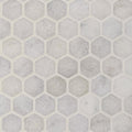 Close detail of tumbled Carrara white marble hexagons showing rounded edges and grey veining