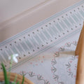 A decorative border of adventuras palma olive porcelain with light gray triangles and dark gray accents on pale blue background