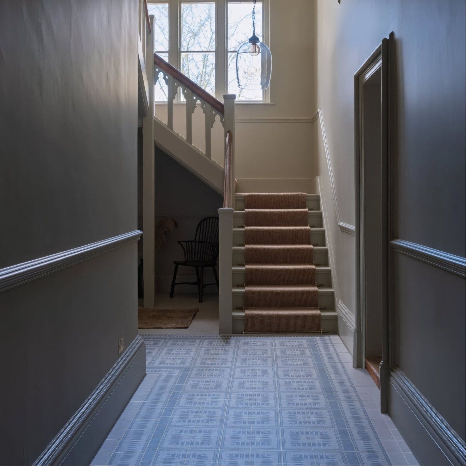 Beige carpeted staircase with wooden balusters and hanging glass pendant light above in adventuras ziggy corner blue porcelain setting