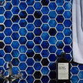 Akazu Porcelain Cobalt Mosaic deep blue hexagonal porcelain mosaic tiles styled with a glass bottle
