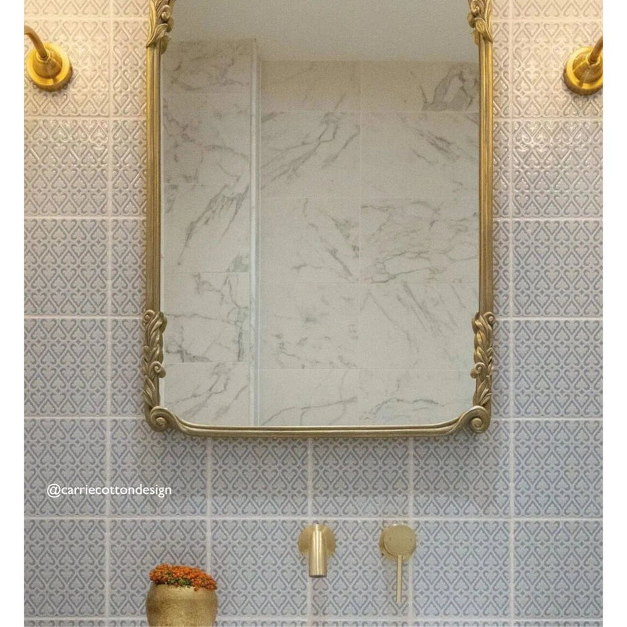 A rectangular mirror with an ornate gold frame and intricate scrollwork in alhambra grey decor 2 glazed tile background