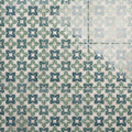 Vintage-style alma green ceramic tiles with repeating quatrefoil pattern in muted green and blue on off-white background