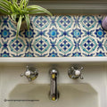 Chrome finished faucet with hot and cold knobs in a white ceramic sink under Andalucia Morena blue patterned tile