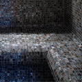 Shimmering iridescent anthracite 25mm square mosaic tiles in blue and silver forming a curved bench