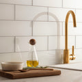 Arctic Clear Glass 300 x 100mm clear glass tiles shown with a gold-toned tap above a sink