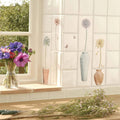 A clear glass vase with vibrant purple pink and red anemones featured in arctotis on off white design